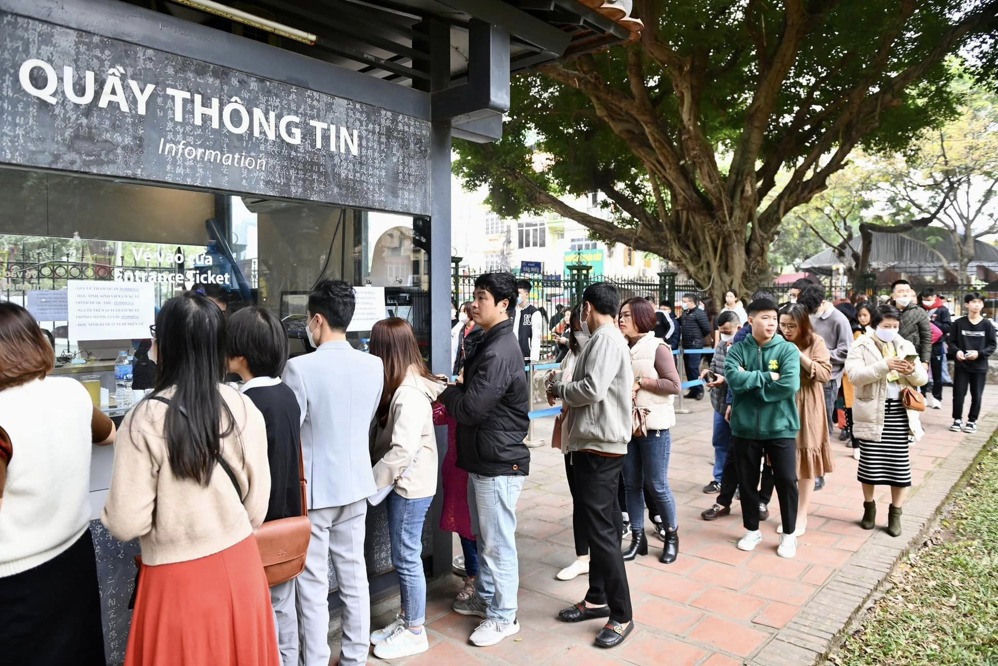 Một nhóm du khách đang xếp hàng ngay ngắn để vào cổng Văn Miếu Quốc Tử Giám