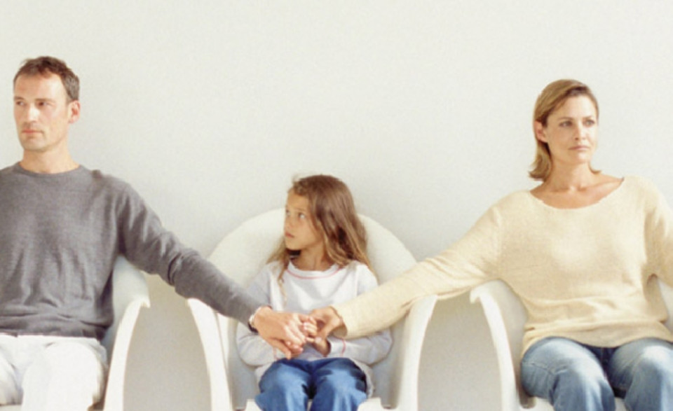 Một người phụ nữ trẻ ngồi tựa lưng vào cửa sổ, tay ôm mặt với vẻ mặt buồn bã, gợi nhớ đến những tác động tiêu cực từ quá khứ và gia đình