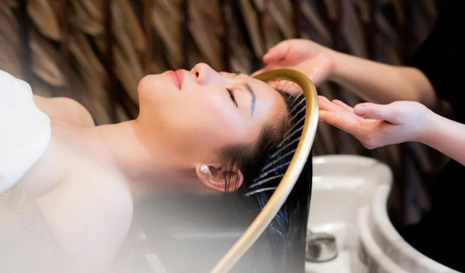 Khách hàng nằm thư giãn trong không gian spa ấm cúng, đang được massage đầu