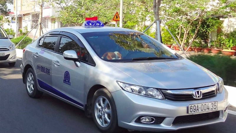 Một chiếc taxi 1/5 màu trắng với biểu tượng độc đáo, thể hiện sự linh hoạt và tiện nghi của dịch vụ xe 7 chỗ