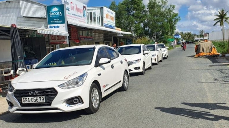Một chiếc taxi Đất Mũi màu vàng tươi sáng đang di chuyển trên đường, biểu tượng cho sự am hiểu và nhanh chóng của dịch vụ địa phương